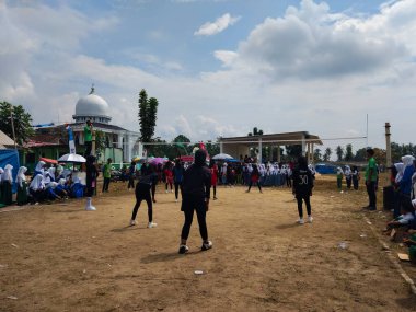 LAMPUNG, INDONESIA - 03 Ağustos 2025: Güneşli bir günde kızlar voleybol oynuyor, seyirciler ve hakem izliyor, Endonezya, 3 Ağustos 2025.