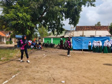LAMPUNG, INDONESIA - 03 Ağustos 2025: Güneşli bir günde kızlar voleybol oynuyor, seyirciler ve hakem izliyor, Endonezya, 3 Ağustos 2025.