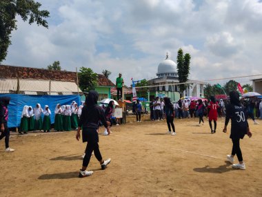 LAMPUNG, INDONESIA - 03 Ağustos 2025: Güneşli bir günde kızlar voleybol oynuyor, seyirciler ve hakem izliyor, Endonezya, 3 Ağustos 2025.