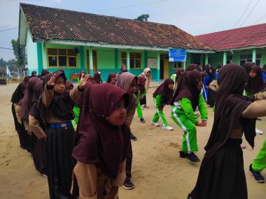 LAMPUNG, INDONESIA - 03 Ağustos 2025: Bir okul etkinliği sırasında bir grup yeşil üniformalı ve kahverengi tesettürlü öğrenci ayakta duruyor. Endonezya 3 Ağustos 2025.