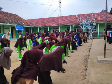 LAMPUNG, INDONESIA - 03 Ağustos 2025: Bir okul etkinliği sırasında bir grup yeşil üniformalı ve kahverengi tesettürlü öğrenci ayakta duruyor. Endonezya 3 Ağustos 2025.