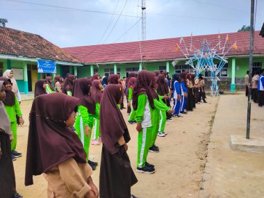 LAMPUNG, INDONESIA - 03 Ağustos 2025: Bir okul etkinliği sırasında bir grup yeşil üniformalı ve kahverengi tesettürlü öğrenci ayakta duruyor. Endonezya 3 Ağustos 2025.