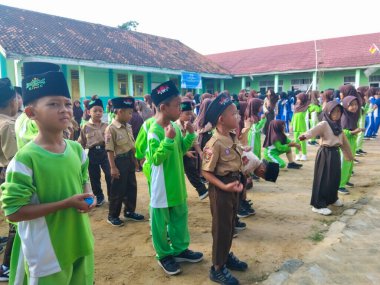 LAMPUNG, INDONESIA - 03 Ağustos 2025: Bir okul etkinliği sırasında bir grup yeşil üniformalı ve kahverengi tesettürlü öğrenci ayakta duruyor. Endonezya 3 Ağustos 2025.