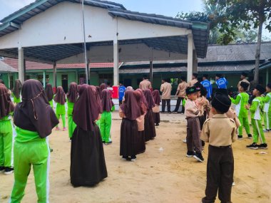 LAMPUNG, INDONESIA - 03 Ağustos 2025: Bir okul etkinliği sırasında bir grup yeşil üniformalı ve kahverengi tesettürlü öğrenci ayakta duruyor. Endonezya 3 Ağustos 2025.