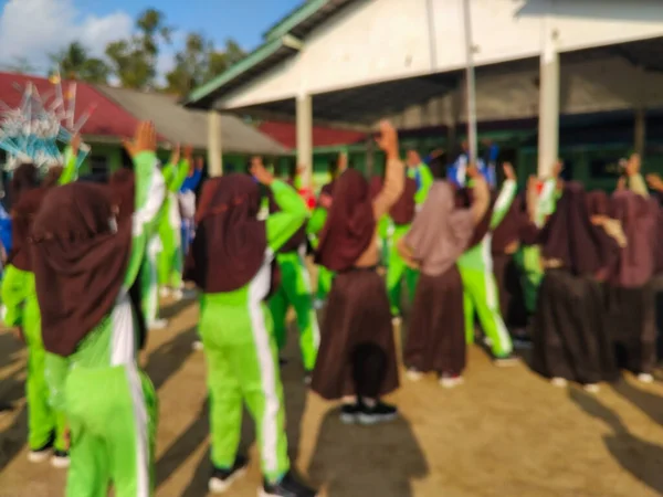 LAMPUNG, INDONESIA - 03 Ağustos 2025: Bir okul etkinliği sırasında bir grup yeşil üniformalı ve kahverengi tesettürlü öğrenci ayakta duruyor. Endonezya 3 Ağustos 2025.