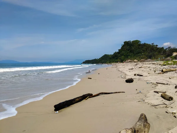 Yumuşak okyanus dalgalarının berrak mavi gökyüzünün altında kumlu bir sahile vuruşunun huzurlu görüntüsü.