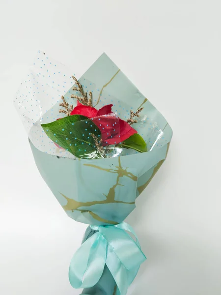 Yeşil yapraklı ve dekoratif dolgulu tek bir kırmızı gül içeren güzel bir buket.