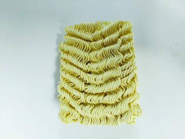 Temiz beyaz bir arkaplana yerleştirilmiş pişmemiş hazır eriştenin yakın plan çekimi.