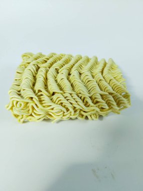 Temiz beyaz bir arkaplana yerleştirilmiş pişmemiş hazır eriştenin yakın plan çekimi.