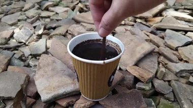 Dışarıdaki taşralı bir yüzeye konmuş kahverengi, tek kullanımlık kağıt bardakta servis edilen sade bir kahvenin yakın çekimi.