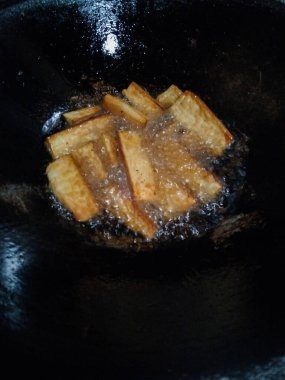 Altın kaju dilimleri geleneksel bir tavada kızgın yağda kızartılıyor.