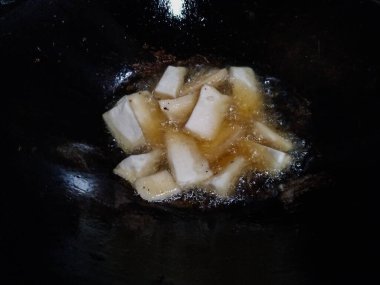 Altın kaju dilimleri geleneksel bir tavada kızgın yağda kızartılıyor.