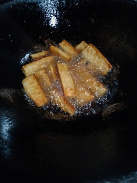 Altın kaju dilimleri geleneksel bir tavada kızgın yağda kızartılıyor.