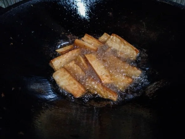 Altın kaju dilimleri geleneksel bir tavada kızgın yağda kızartılıyor.