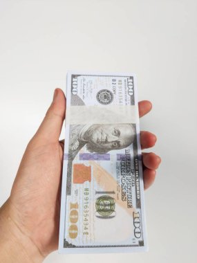 Temiz beyaz arka planda izole edilmiş kağıt bir bantla korunan 100 dolarlık banknotları tutan bir el.