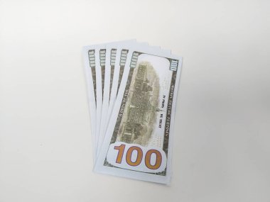 Temiz beyaz arka plana yayılmış 100 dolarlık banknotlar.