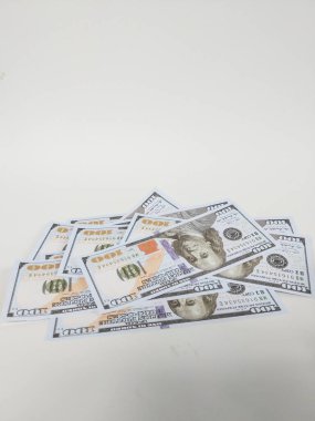Birkaç yüz dolarlık banknotlar temiz beyaz bir arkaplana rastgele dağılmış.