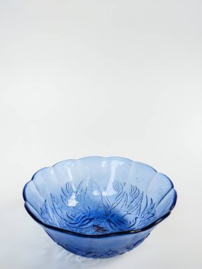 İç yüzeyine oyulmuş zarif çiçek desenli şeffaf mavi bir cam kase.