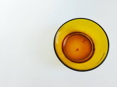 Temiz beyaz arka plana yerleştirilmiş boş bir kehribar cam kasenin minimalist bir stüdyo çekimi.