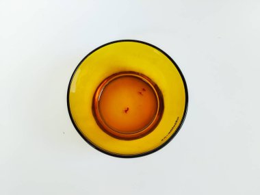 Temiz beyaz arka plana yerleştirilmiş boş bir kehribar cam kasenin minimalist bir stüdyo çekimi.