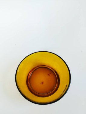 Temiz beyaz arka plana yerleştirilmiş boş bir kehribar cam kasenin minimalist bir stüdyo çekimi.