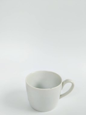 Boş beyaz bir seramik kupanın minimalist bir stüdyo fotoğrafı temiz beyaz bir arka plana yerleştirilmiş..