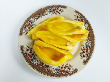 Taze olgun meyve segmentleri beyaz bir arka planda izole edilmiş, klasik desenli seramik bir plakaya dizilmiş.