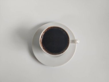 Siyah kahve dolu beyaz bir seramik fincanın minimalist fotoğrafı.
