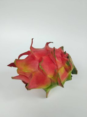 Canlı kırmızı derili ve yeşil uçlu olgun bir ejderha meyvesi temiz bir şekilde gösterilir.