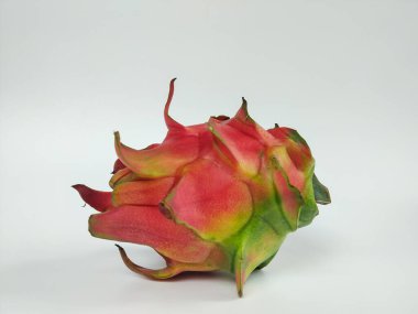 Canlı kırmızı derili ve yeşil uçlu olgun bir ejderha meyvesi temiz bir şekilde gösterilir.