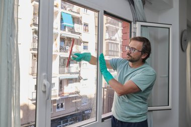 Evdeki pencereleri temizleyen adam. Lastik eldiven giyen, bardağı sünger ve spreyle yıkayan biri. Birlikte ev işi yapan bir çift. Ev temizliği, hijyen ve ev hayatı kavramı