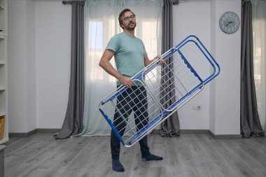 Kadın ve erkek çamaşırlarını evde kurutuyorlar. Kurutma askısına asılan ve temiz giysiler katlanan bir çift. Ev işleri, ev işleri ve günlük rutin işler kavramı.