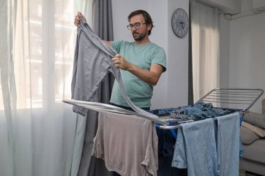 Kadın ve erkek çamaşırlarını evde kurutuyorlar. Kurutma askısına asılan ve temiz giysiler katlanan bir çift. Ev işleri, ev işleri ve günlük rutin işler kavramı.