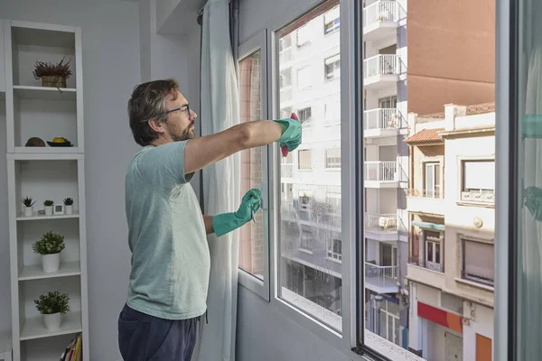 Evdeki pencereleri temizleyen adam. Lastik eldiven giyen, bardağı sünger ve spreyle yıkayan biri. Birlikte ev işi yapan bir çift. Ev temizliği, hijyen ve ev hayatı kavramı