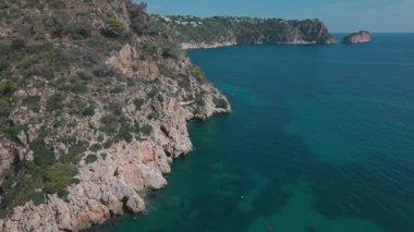 İspanya 'nın Javea kentindeki Cala Granadella plajı yakınlarındaki engebeli kayalıkların ve turkuaz Akdeniz suyunun insansız hava aracı görüntüleri. Çarpıcı sahil manzarasının havadan görünüşü.