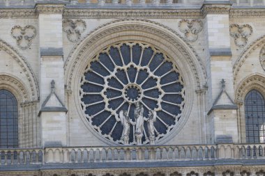 Paris, Fransa 'daki Notre Dame Katedrali' nin ön cephesindeki gül penceresi ve taş heykellerin yakın görüntüsü.