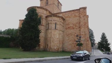 Avila İspanya 'da bir ortaçağ taşından kilisenin virajlı bir caddeden geçen bir arabasının sinematik bir çekimi..