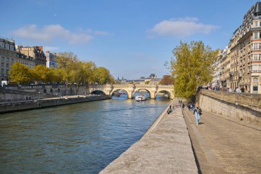 Güneşli bir sonbahar gününde Paris 'teki Seine Nehri' ni tekneler ve tarihi binalarla geçen Pont Neuf köprüsünün manzarası. Paris, Fransa - 11 Ekim 2025.