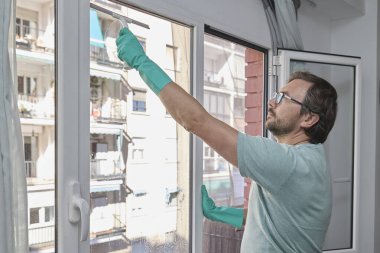 Evdeki pencereleri temizleyen adam. Lastik eldiven giyen, bardağı sünger ve spreyle yıkayan biri. Birlikte ev işi yapan bir çift. Ev temizliği, hijyen ve ev hayatı kavramı