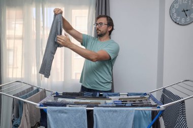 Kadın ve erkek çamaşırlarını evde kurutuyorlar. Kurutma askısına asılan ve temiz giysiler katlanan bir çift. Ev işleri, ev işleri ve günlük rutin işler kavramı.