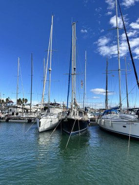 Güneşli bir günde sakin bir marinada demirlemiş yelkenliler sakin bir sahil hayatı ve deniz eğlencesi yansıtıyor. Valencia, İspanya - 8 Kasım 2025.