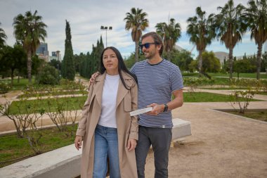 Parkta bir kitapla birlikte duran çift..