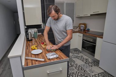A man closes a plastic food container on a kitchen counter while organizing prepared meals.