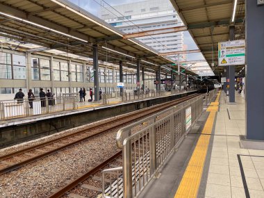 Platformda rayları ve yolcuları olan Japon tren istasyonu. Hiroşima, Japonya - 1 Kasım 2025.