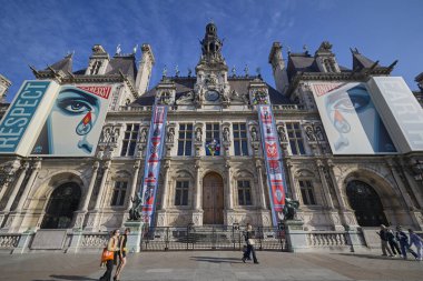 Paris 'teki Hotel de Ville' in geniş bir manzarası, büyük sanat afişleri ve güneşli bir günde meydanda yürüyen insanlar. Tarihi mimari ve şehir yaşam tarzı. Paris, Fransa - 11 Ekim 2025.