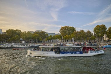 Paris 'teki Seine Nehri boyunca demirlemiş tekneler konut binaları ve yumuşak bir akşam gökyüzünün altında sonbahar ağaçları vardı. Paris, Fransa - 11 Ekim 2025.
