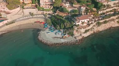 Moraira Körfezi 'nin hava aracı görüntüsü. Kıyıda küçük botlar ve renkli kanolar var. İspanya, Costa Blanca 'nın manzaralı kıyı manzarası, villaları ve turkuaz deniz manzarası..