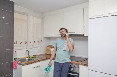 Modern mutfakta lastik eldiven tutan akıllı telefon kullanan bir adam..