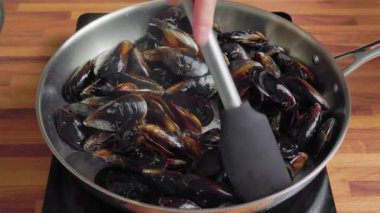 Mutfak ocağındaki paslanmaz çelik bir tavaya yerleştirilmiş taze çiğ midyeleri kapatın. Deniz ürünleri pişirme hazırlama süreci, sağlıklı Akdeniz yemekleri, ev yemeği konsepti..