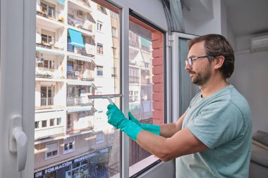 Ev işleri sırasında pencereleri temizleyen adam.